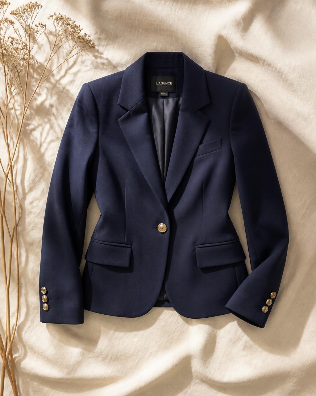A navy tailored blazer laid on cream linen